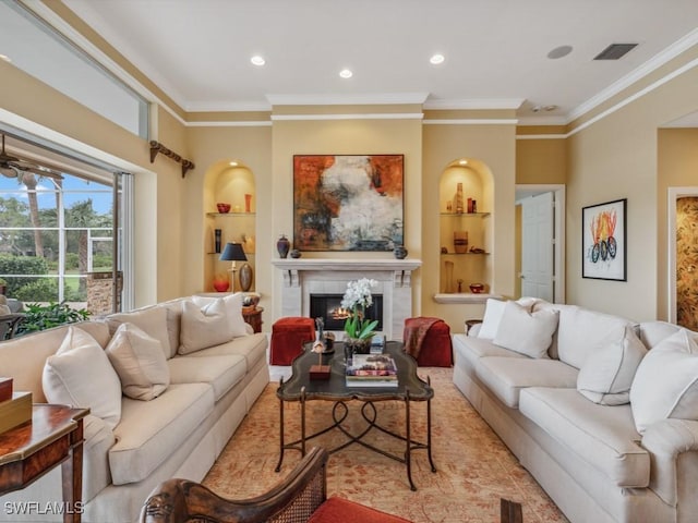 living room with crown molding, built in shelves, and a tile fireplace