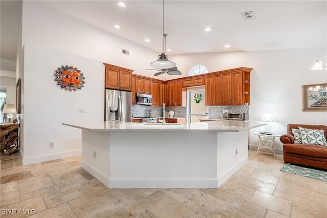 kitchen with decorative backsplash, hanging light fixtures, appliances with stainless steel finishes, and a large island