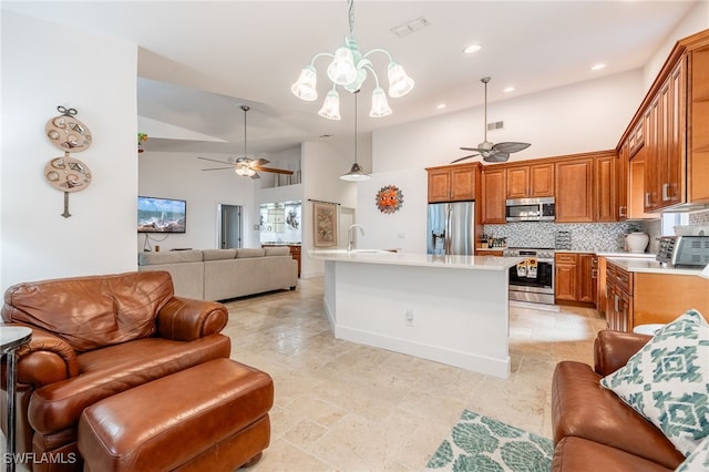 kitchen featuring appliances with stainless steel finishes, a towering ceiling, decorative light fixtures, decorative backsplash, and sink