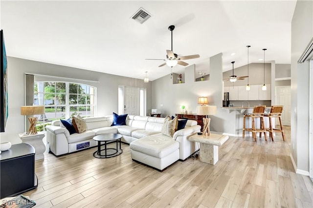 living room with ceiling fan, vaulted ceiling, and light wood-type flooring