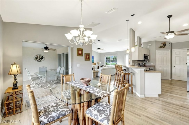 dining space featuring ceiling fan with notable chandelier, light hardwood / wood-style flooring, and lofted ceiling