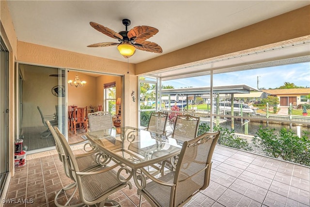 sunroom / solarium with ceiling fan with notable chandelier and a water view