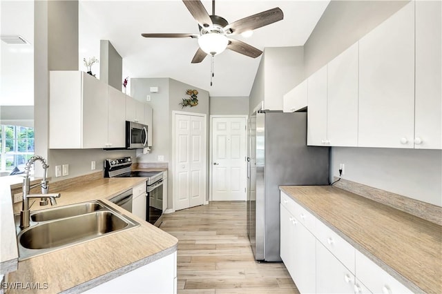 kitchen with white cabinetry, stainless steel appliances, sink, ceiling fan, and light hardwood / wood-style flooring