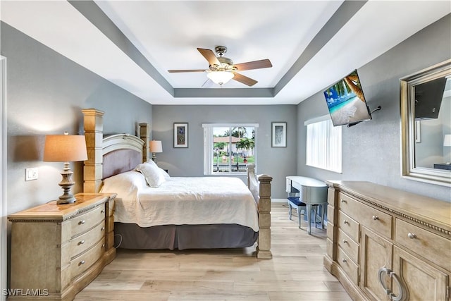 bedroom featuring ceiling fan, a raised ceiling, and light hardwood / wood-style flooring