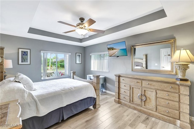 bedroom featuring ceiling fan, light hardwood / wood-style floors, and a raised ceiling