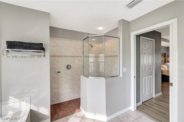 bathroom with tiled shower and tile patterned flooring