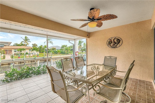 sunroom / solarium with ceiling fan and a water view