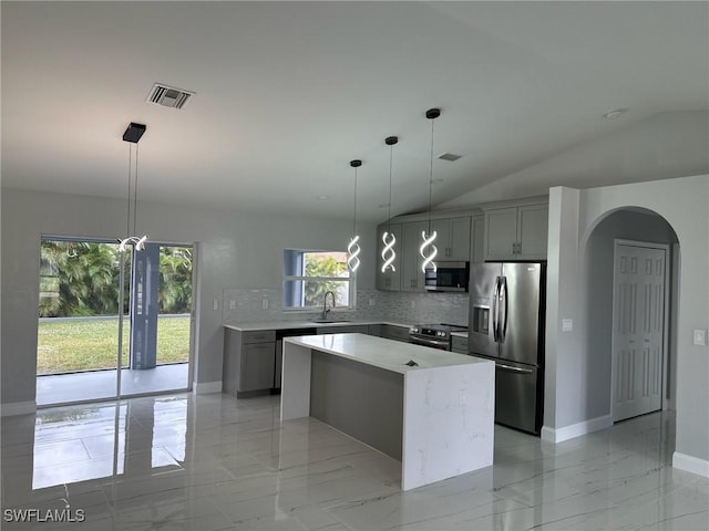 kitchen featuring backsplash, appliances with stainless steel finishes, gray cabinetry, and a kitchen island