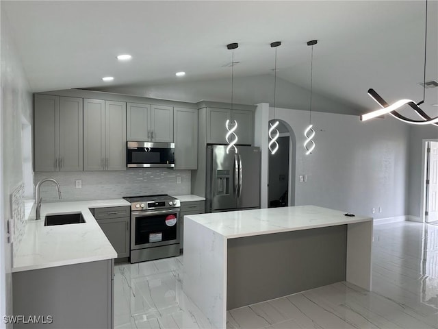 kitchen featuring appliances with stainless steel finishes, lofted ceiling, a kitchen island, and sink