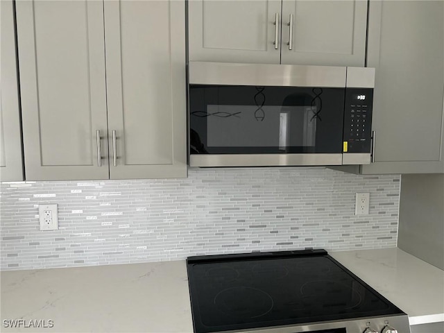 interior details featuring stainless steel appliances, decorative backsplash, and light stone counters