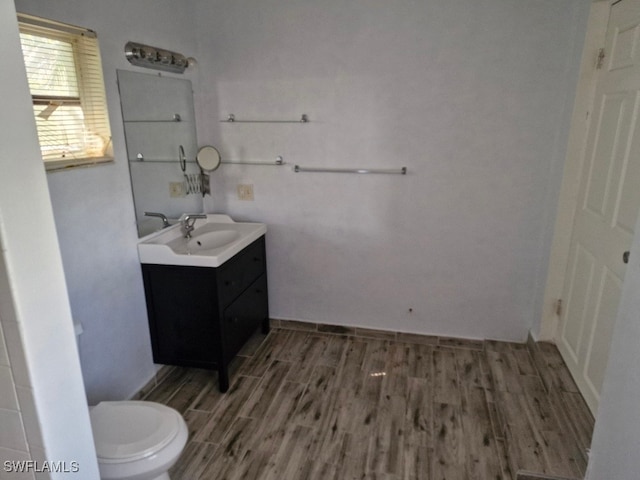 bathroom with toilet, wood finished floors, and vanity