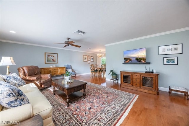 living room with ceiling fan with notable chandelier, light hardwood / wood-style flooring, and ornamental molding