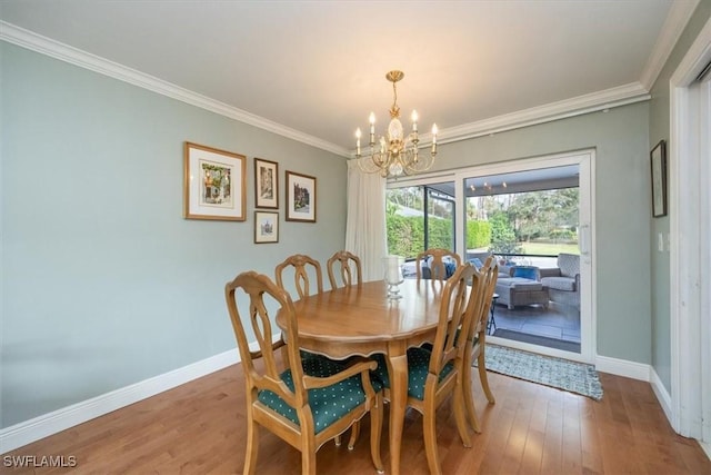 dining room featuring hardwood / wood-style flooring, ornamental molding, and an inviting chandelier