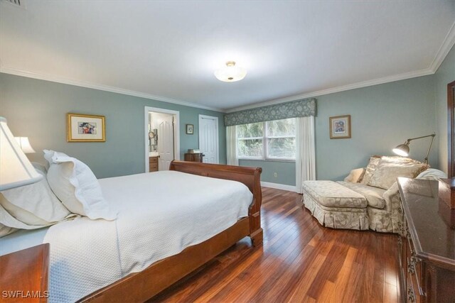 bedroom with crown molding, ensuite bath, and dark wood-type flooring