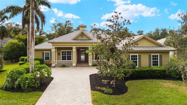 view of front of house with a porch, a front yard, and decorative driveway