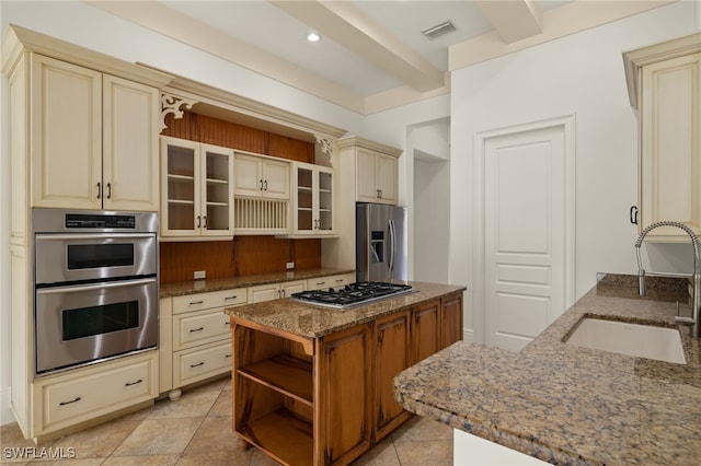 kitchen featuring cream cabinetry, sink, dark stone countertops, and stainless steel appliances