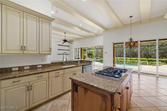 kitchen with stainless steel appliances, decorative light fixtures, sink, dark stone counters, and beamed ceiling