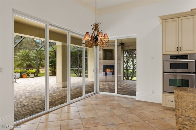 entryway with light tile patterned flooring and ceiling fan with notable chandelier