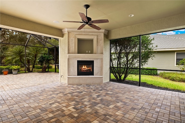 unfurnished sunroom with ceiling fan and a fireplace