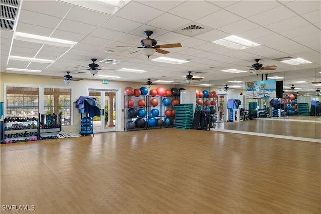 gym with ceiling fan, visible vents, a drop ceiling, and wood finished floors