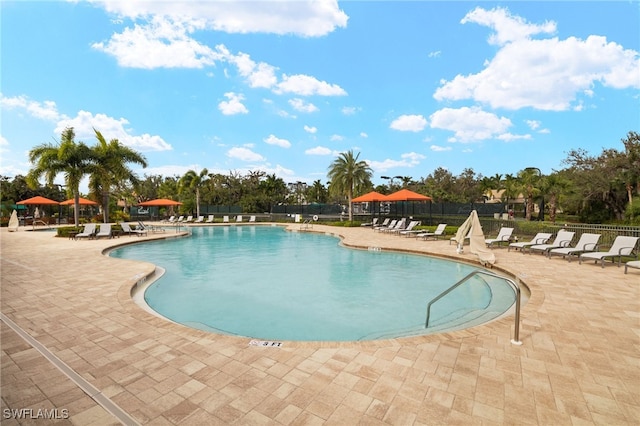 community pool with fence and a patio area