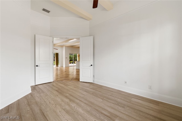 spare room with ceiling fan, light hardwood / wood-style floors, and beam ceiling