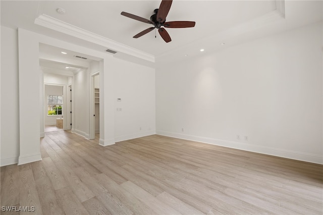 spare room with ceiling fan, a tray ceiling, ornamental molding, and light wood-type flooring