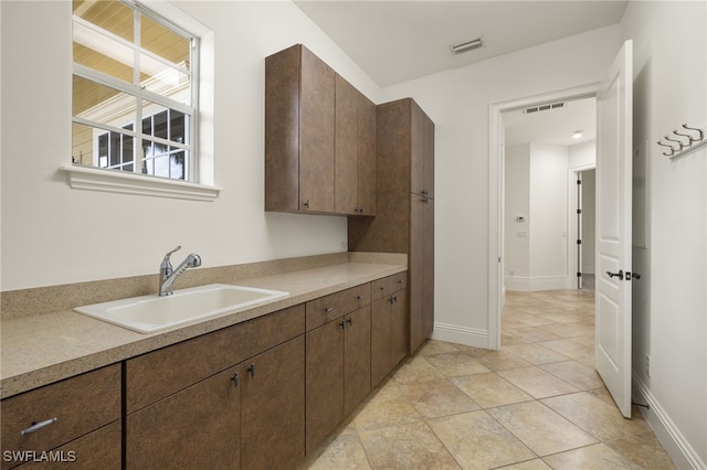 kitchen with sink, dark brown cabinets, and light tile patterned flooring