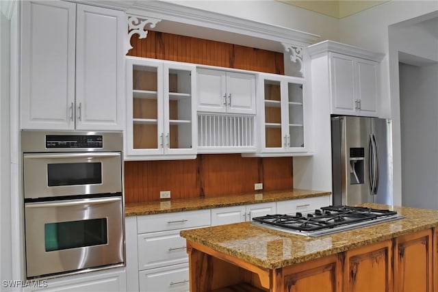 kitchen featuring glass insert cabinets, white cabinetry, stainless steel appliances, and a center island