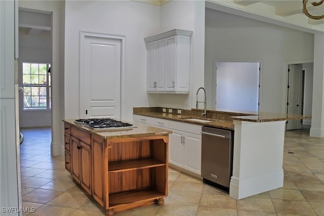 kitchen with white cabinetry, open shelves, stainless steel appliances, dark stone countertops, and a sink