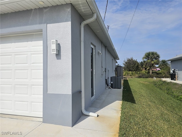 view of property exterior with a garage, cooling unit, and a yard