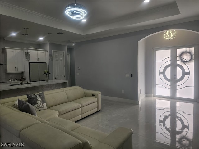 living room with sink, a tray ceiling, and ornamental molding