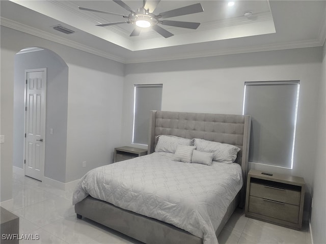 bedroom with ceiling fan, a tray ceiling, and ornamental molding