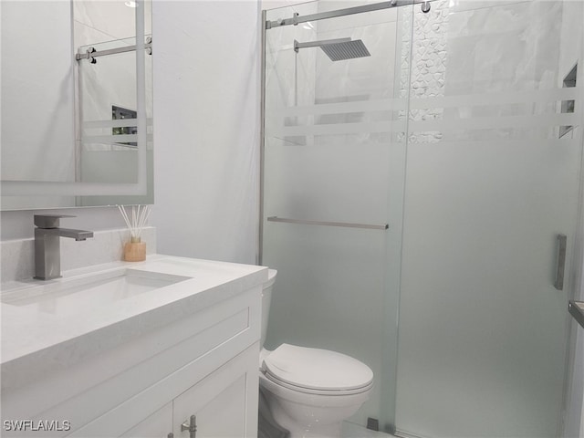 bathroom with toilet, vanity, and a shower with door