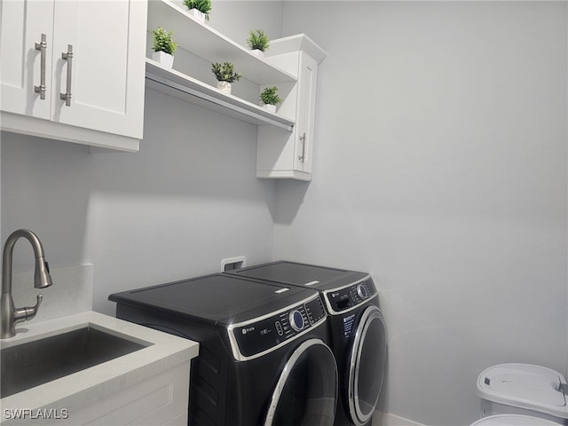 laundry room with sink, washing machine and clothes dryer, and cabinets