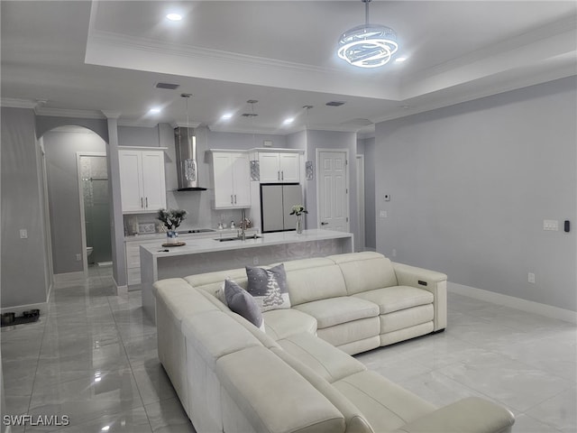 living room with a raised ceiling, sink, and crown molding