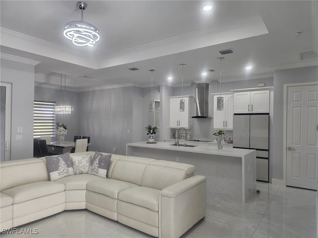 living room featuring sink, a tray ceiling, ornamental molding, and an inviting chandelier