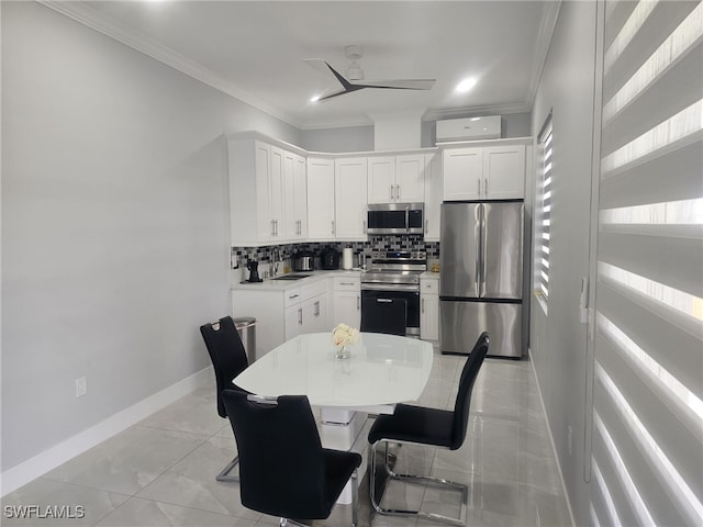 kitchen with white cabinetry, a breakfast bar area, stainless steel appliances, ceiling fan, and crown molding