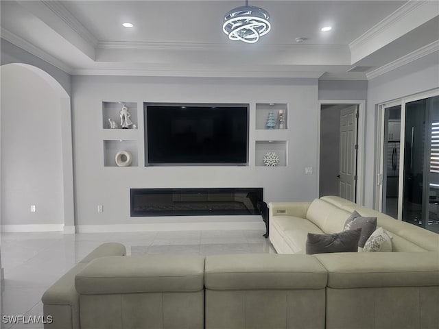 living room with ornamental molding, a raised ceiling, and built in shelves