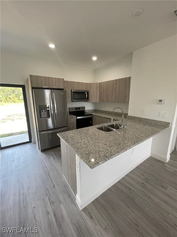 kitchen with sink, kitchen peninsula, dark hardwood / wood-style floors, and stainless steel appliances