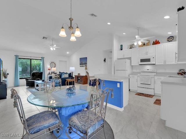 dining area featuring vaulted ceiling, sink, and ceiling fan with notable chandelier