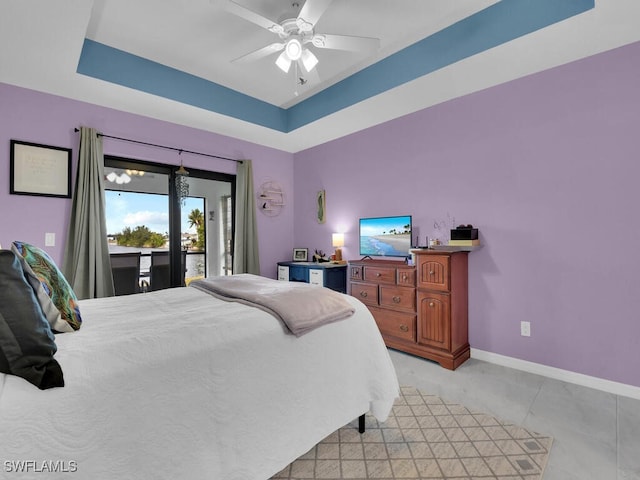 bedroom featuring ceiling fan, a tray ceiling, and access to outside