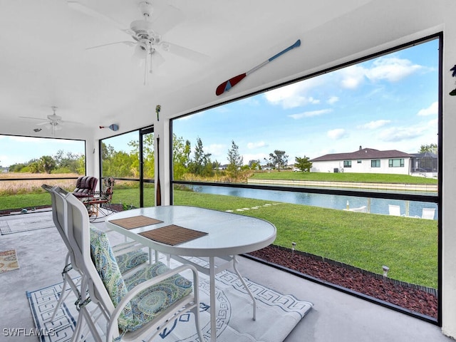 sunroom / solarium featuring ceiling fan and a water view