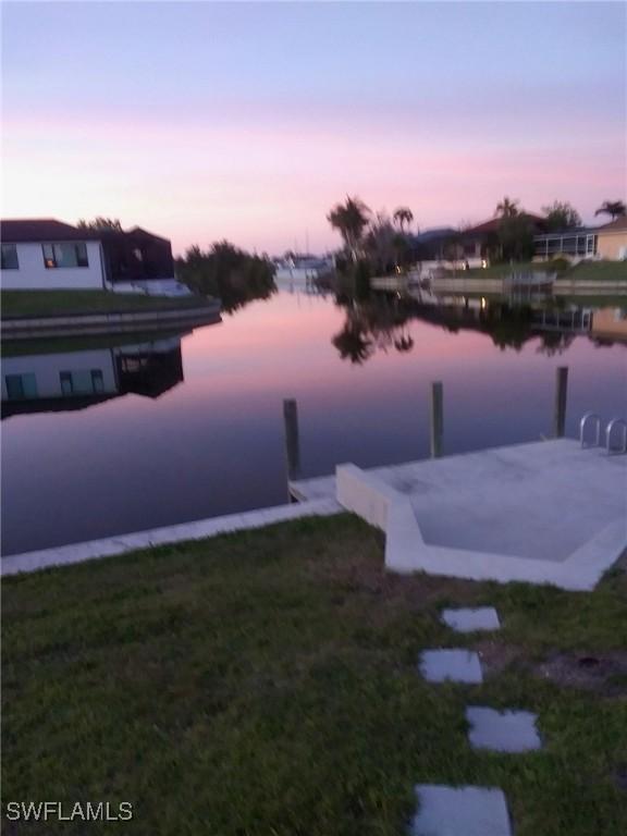 view of dock with a yard and a water view