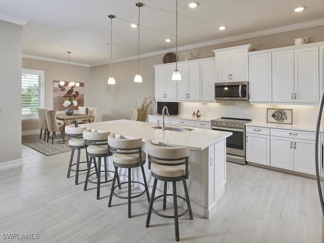 kitchen featuring pendant lighting, white cabinetry, a kitchen island with sink, and appliances with stainless steel finishes