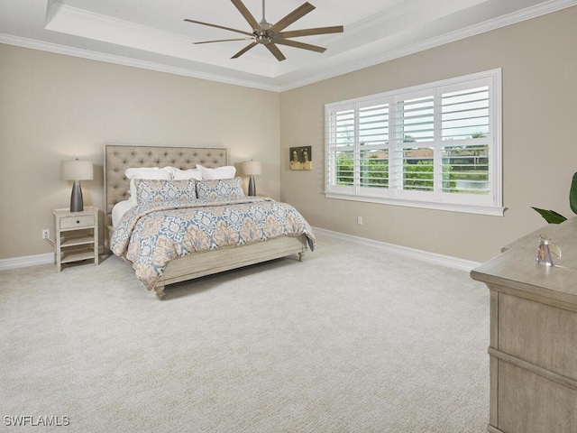 carpeted bedroom with ornamental molding, ceiling fan, and a tray ceiling