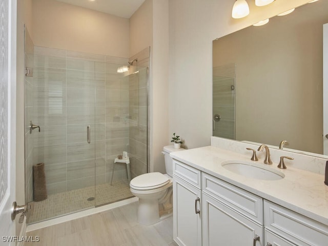 bathroom featuring an enclosed shower, vanity, and toilet