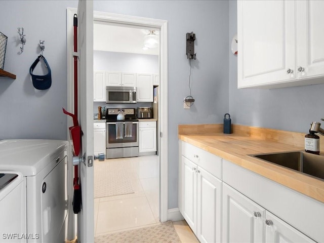 laundry area featuring cabinets, light tile patterned floors, independent washer and dryer, and sink