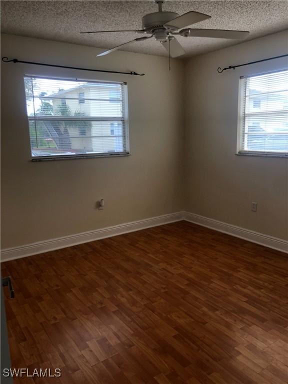 unfurnished room featuring ceiling fan, dark wood-type flooring, and a textured ceiling