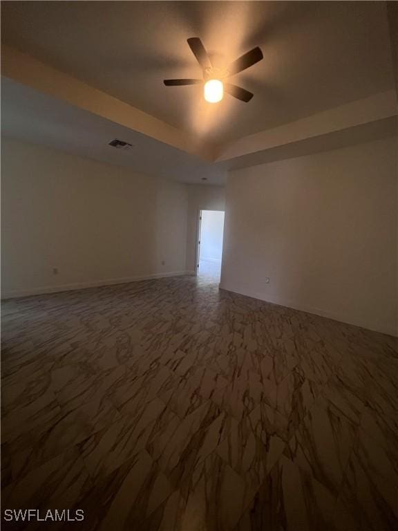 spare room featuring ceiling fan and a tray ceiling